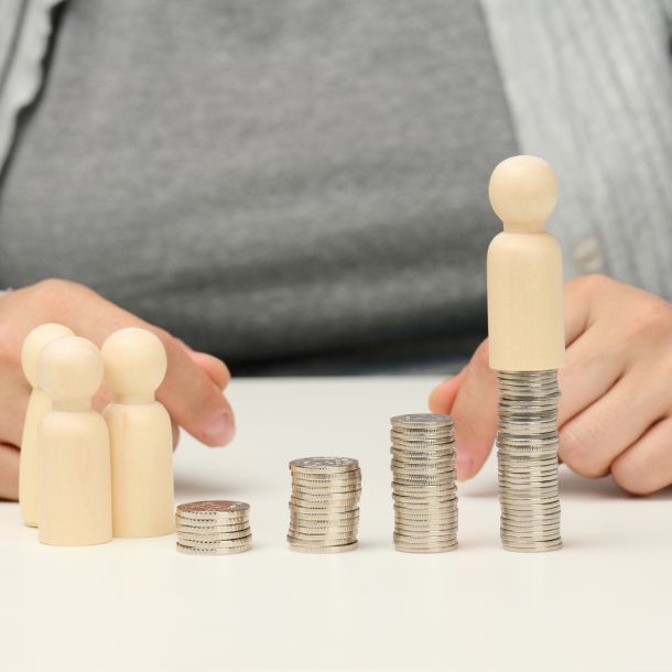 Representación gráfica de la pensión alimenticia con monedas y muñecos de madera