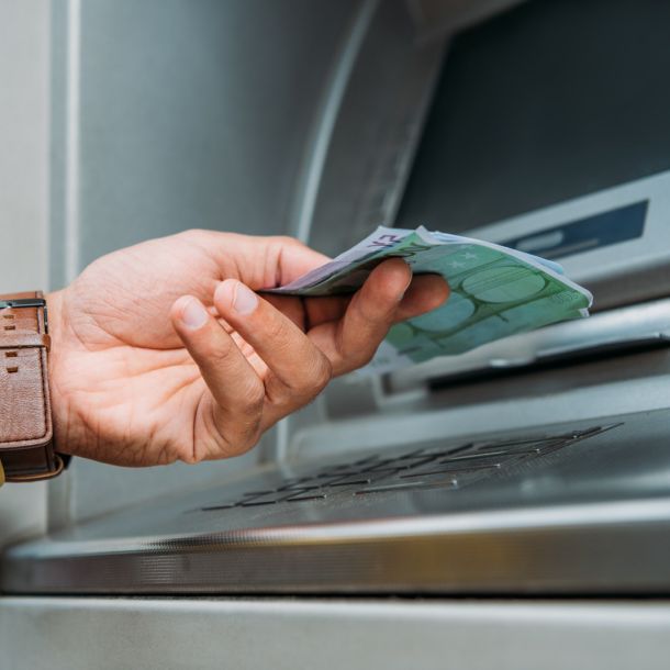 Una mano recoge el dinero de un cajero automático de una reclamación realizada a su banco